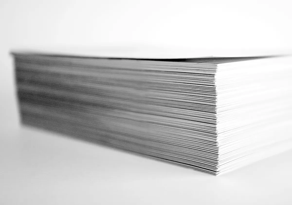 A thick, neatly squared stack of white paper on a white surface.
